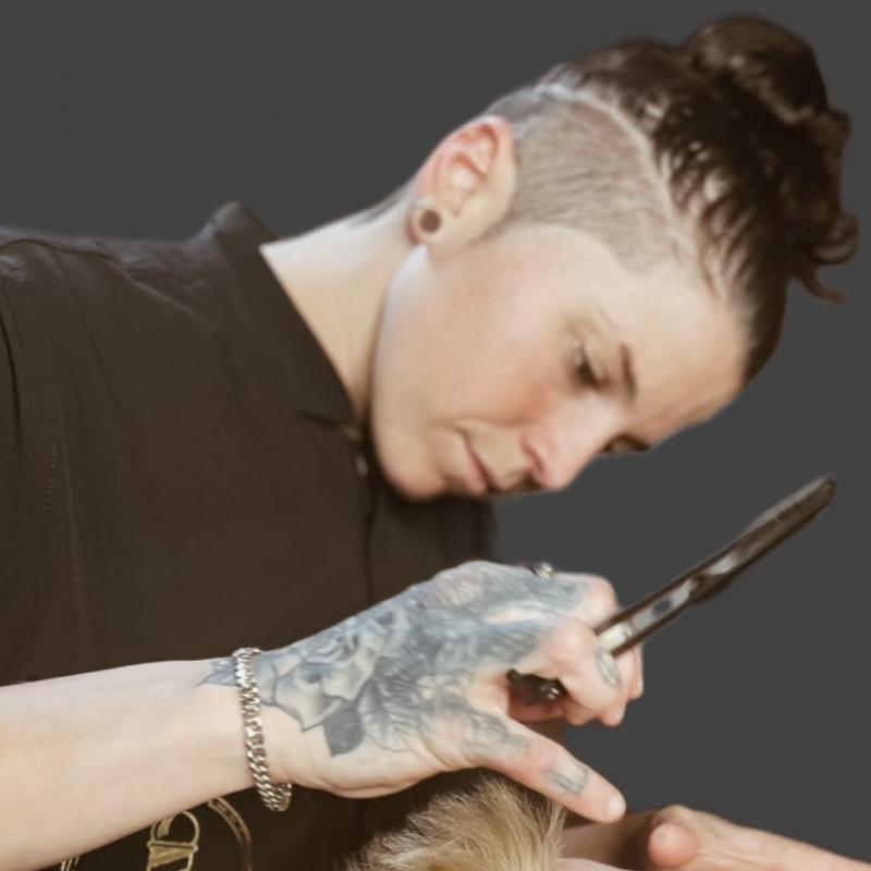 Barber demonstrating precision barbering technique at Cut to a T